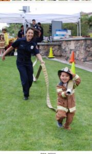 A firefighter running after a kid in a firefighter costume