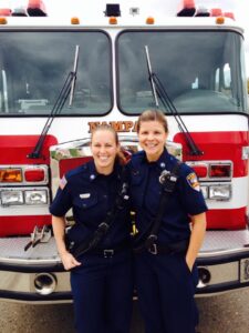 Two firefighters with arms around each other and smiling