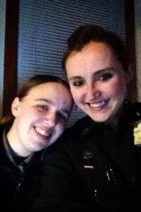 Two women wearing black uniforms smiling