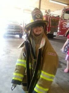A kid wearing a firefighter’s uniform